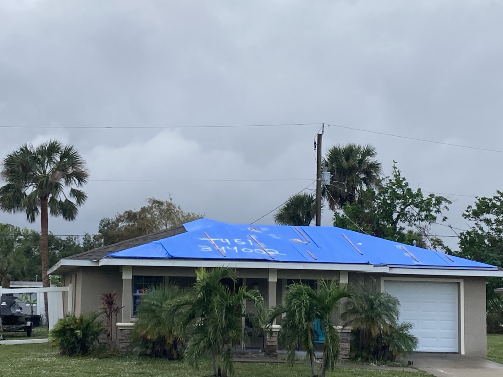 Blue emergency tarp securely installed over a storm-damaged roof in the Tampa, Florida area